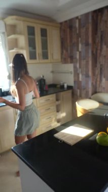 Bir kadın taze meyvelerle dolu parlak, modern mutfağında ferahlatıcı ve sağlıklı bir meyve suyu hazırlar.