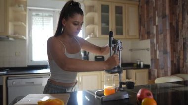 Şık ve modern bir mutfakta, genç bir kadın çeşitli meyveleri ustalıkla suluyor, sağlıklı bir yaşam tarzını teşvik ediyor.