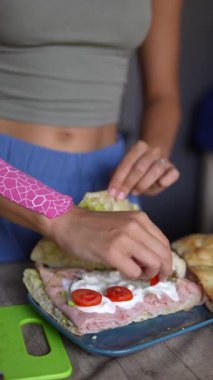 Canlı ve renkli bir sandviç, taze marul, olgun domates ve kremalı malzemelerle ustalıkla hazırlanıyor.