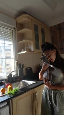 Bir insanın evcil hayvan ve renkli taze sebzelerle eğlendiği davetkar ve ferahlatıcı bir mutfak sahnesi.