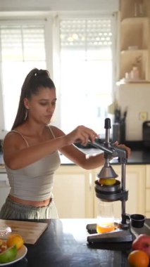 Bir kadın taze meyve suyu hazırlar. Parlak bir mutfakta meyve sıkacağı kullanır. Sağlıklı yaşam ve refahı arttırır..