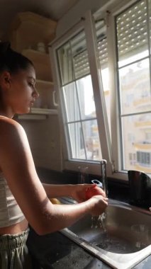 Parlak bir mutfakta kedisiyle neşeyle etkileşime giren bir kadın, mutlu bir ev hayatının özünü yakalıyor.