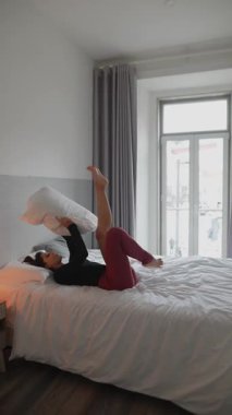 Bir insan yastıkla şatafatlı bir şekilde etkileşime girer. Yatak odası dekorasyonu, boş zamanlarını ve yaratıcılığını gösterir..