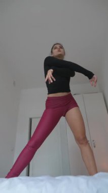 Bireylerin şık atletik giysiler giydiği, dinamik bir esneme hareketi gösteren büyüleyici bir iç mekan sahnesi.