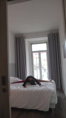 Esnek bir birey yatakta zarif bir gerinme gerçekleştirir, dinamik hareket ve dengeyi gösterir..