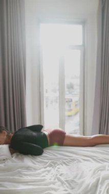 Yoga yapan esnek bir birey, güneşli bir odadaki bir yatağa uzanıyor, hareket ve zarafet sergiliyor..