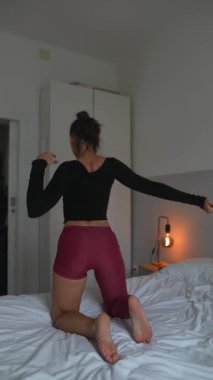 Yetenekli bir dansçı, rahat bir yatakta şık bir gecelik giyerken anlamlı hareketlerini gururla sergiler.