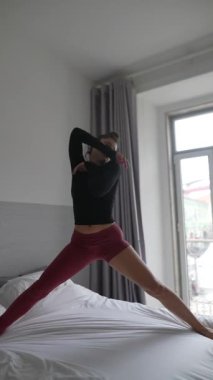 Yetenekli bir dansçı yatak odasının rahat ve güneşli atmosferinde zarif hareketler sergiler.