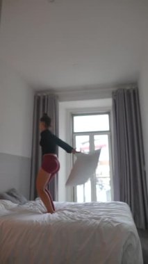 Şık bir odada rahat bir yastıkla neşeli ve yaratıcı hareketler yapan bir dansçının olduğu canlı bir an.