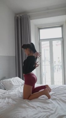 Bir insan dinamik ve anlamlı dans pozlarıyla kendini ifade eder. Parlak, havadar, davetkar bir yatak odasında.