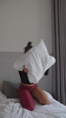 Bir insan rahat bir yatak odası ortamında yumuşak bir yastığı sıcacık kucaklar ve güzel bir rahatlama anı yakalar.