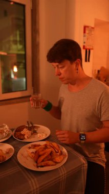 Bir insan, sıcak ve davetkar bir ortamda kızarmış patates eşliğinde lezzetli bir yemeğin tadını çıkarıyor.