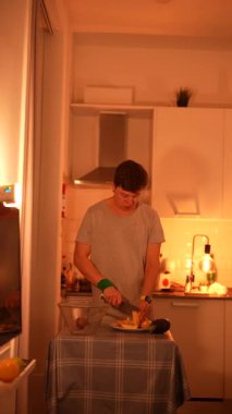 Güzelce aydınlatılmış bir mutfak ortamında genç bir adam ustalıkla bir dizi taze meyve hazırlar.