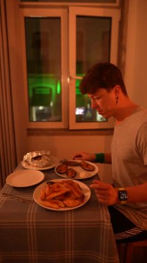 Bir insan, rahat bir atmosferde sıcak ışıkla çevrili bir masada lezzetli bir yemeğin tadını çıkarıyor.