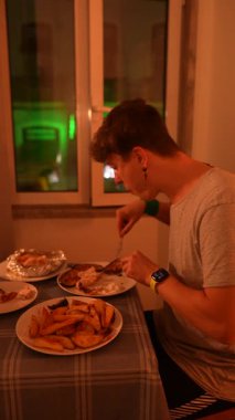 Genç bir adam, kıtır kıtır altın kızartmalar ve çeşitli lezzetli yemeklerin yer aldığı lezzetli bir gecikme yemeğinin keyfini çıkarıyor.