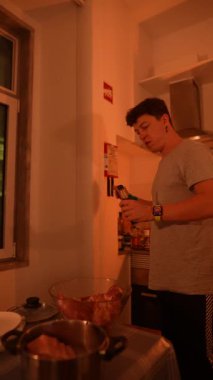 Sıcak bir mutfakta, genç bir insan aşçılık yeteneklerini sergilemek için çeşitli malzemeler hazırlar.