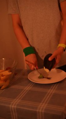 Bir insan patlıcanları ustalıkla keserken aynı zamanda sağlıklı yemek pişirme ve taze malzemeler kullanma prensiplerine odaklanır.