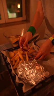 Taze patatesler, lezzetli sosisler ve rahat bir masada folyoya sarılı bir tabakla ilgi çekici bir yemek sahnesi.