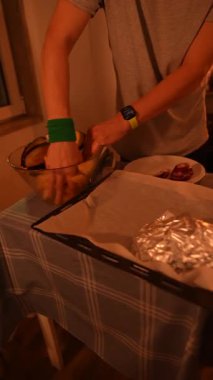 Bir insan ustalıkla yemek hazırlıyor, aile ve arkadaşlar için rahat bir ortamda yaratıcılık sergiliyor.