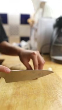 Taze sarımsak karanfillerini ustalıkla dilimleyen yakın plan bir ahşap kesim tahtası.