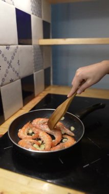 Tavada karidesi ustalıkla karıştıran bir el taze ve kaliteli malzemelerle enfes yemek yapma sanatını sergiliyor.