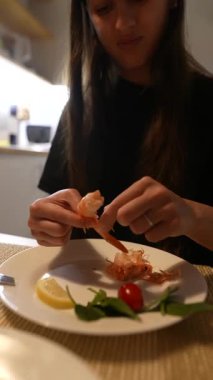 Bir insan, içinde limon ve taze bitkiler bulunan bir tabakta karides soymaktan keyif alır.