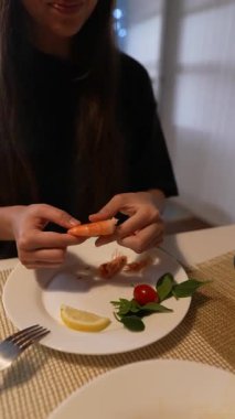 Bir insan zarif bir ortamda limon ve otlarla süslenmiş güzel bir karides yemeğinin tadını çıkarıyor.