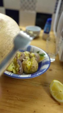 Taze malzemelerle yapılmış güzel bir yemek ve ahşap bir masada bir dilim limon servis eden bir el.