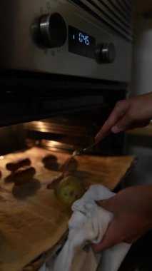 Bir insan fırından altın bir patates ve sosis alır ve detaylı pişirme sürecini vurgular.