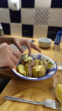 Sıcak bir akşam yemeğinde taze limon dilimleriyle birlikte patatesleri ustalıkla hazırlayan ellerin yakın çekimi.