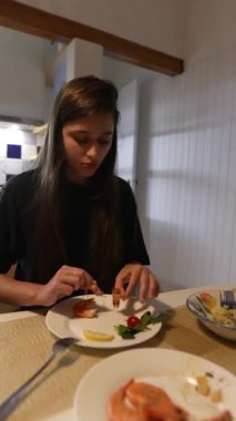 Genç bir kadın taze, canlı sebzeler ve keskin limon içeren lezzetli deniz ürünleri yemeğinin tadını çıkarıyor.