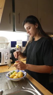 Bir kadın, yemek hazırlıkları sırasında modern ve iyi hazırlanmış mutfağında ustalıkla taze sebzeler hazırlar.