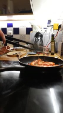 Yetenekli bir şef, rahat ve davetkar bir mutfak ortamında bir yığın lezzetli karides hazırlar.
