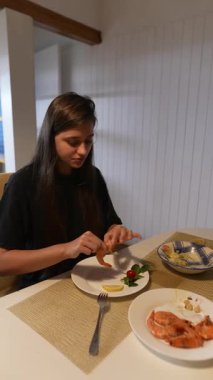 Deniz ürünleri tabağının tadını çıkaran genç bir kadın, her anın tadını çıkararak enfes bir yemek deneyimiyle meşgul.