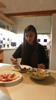 Bir kadın, taze deniz ürünleri, canlı sebzeler ve makarnadan oluşan lezzetli yemeğinin tadını çıkarmaktan mutluluk duyar.