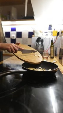 Bir insan lezzetli bir yemeği güzel bir mutfakta aromatik sarımsak ve taze malzemelerle ustaca pişirir.