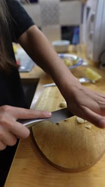 Mutfakta taze sarımsağı ustalıkla dilimleyerek aşçılık becerilerini sergileyen bir insan.