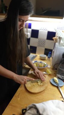 Odaklanmış bir kadın mutfakta yemek pişirme becerilerini ve yaratıcılığını ön plana çıkaran malzemeler hazırlar..