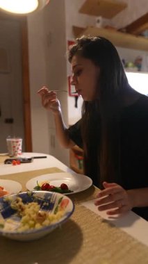 Bir kadın sıcak ve davetkar bir mutfak atmosferinde lezzetli yemeğinin tadını çıkarıyor.