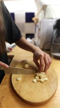 Samimi bir mutfakta taze sarımsak doğramanın titiz sürecini gösteren bir dizi detaylı yakın çekim.