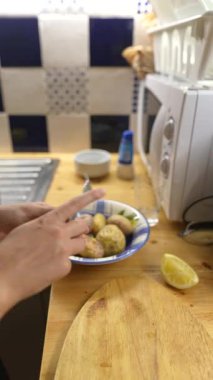 Sıcak bir mutfak ortamında, insan yemek için limonla süslenmiş lezzetli haşlanmış patatesler hazırlar.