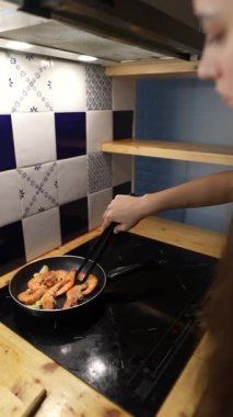 Yetenekli bir birey modern ve şık bir mutfak ortamında karides hazırlar ve pişirir.