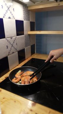 Bu, yemek çubuklarıyla karides pişirirken, şık bir mutfakta etkileyici mutfak becerileri sergilerken çekilmiş yakın plan bir fotoğraf.