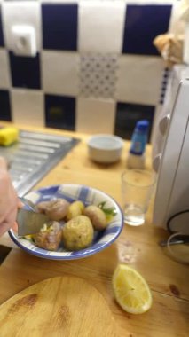 Yetenekli bir aşçı baharatlı patatesleri, limonla birlikte sıcak bir mutfak ortamında ustalıkla hazırlar.