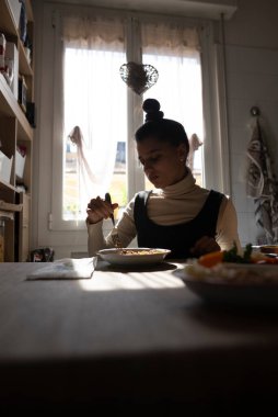 Bir kadın, rahat, güneşli mutfağında, huzurlu bir atmosferde, keyifli bir yemeğin tadını çıkarırken mutluluğu bulur.