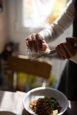Bir insan ustalıkla besleyici ve sağlıklı bir yemeği özenle süslüyor ve ev yemeği sanatını vurguluyor.