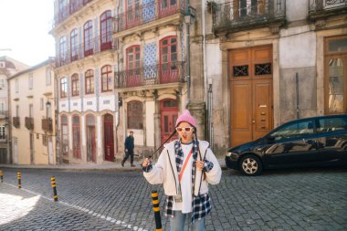 Çok şık bir şahıs renkli binalarla çevrili büyüleyici bir kaldırım taşı caddesinde güven içinde poz veriyor.