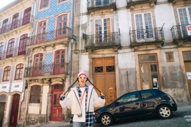 Şık bir birey canlı binaların önünde poz veriyor, şehir ortamında modern moda sergiliyor..