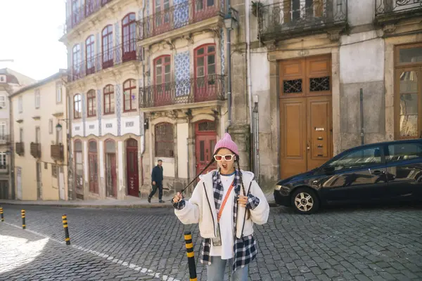 Çok şık bir şahıs renkli binalarla çevrili büyüleyici bir kaldırım taşı caddesinde güven içinde poz veriyor.