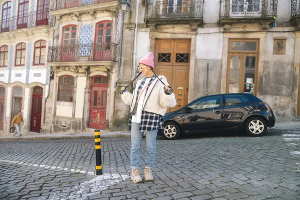 Tarz sahibi genç bir kadın, kendine güvenerek güzel klasik mimarinin yer aldığı pitoresk bir sokak sahnesinde poz veriyor.